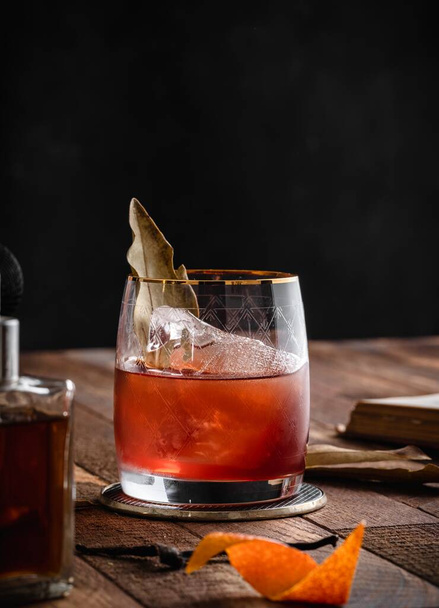 A vertical shot of a brown cocktail in a glass placed on a wooden surface with other drinks - Фото, изображение
