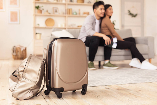 Asijské pár s kufrem čeká sedí na gauči doma - Fotografie, Obrázek