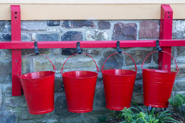 Four red buckets hanging on a wall. Backgound maybe. - Photo, Image