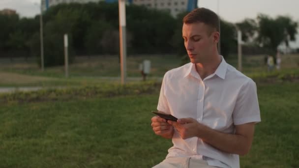 νεαρός άνδρας διαβάζει βιβλίο στο πάρκο - Πλάνα, βίντεο
