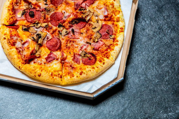 Pizza mediterránea con pepperoni en una caja sobre una mesa
 - Foto, imagen