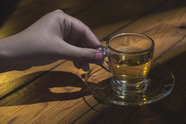 Жіноча рука тримає чашку чаю в драматичному важкому легкому стані
 - Фото, зображення