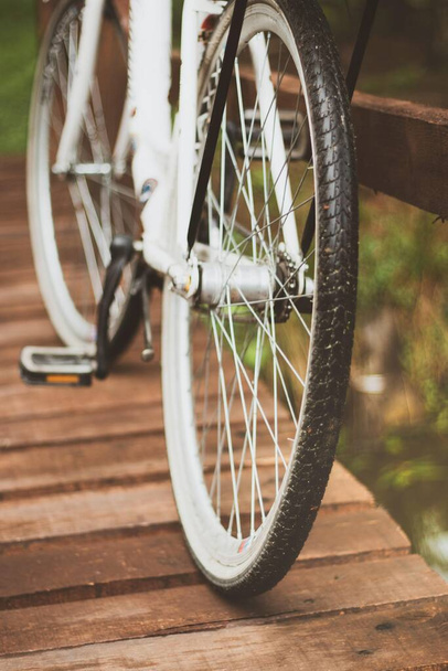 A vertical closeup shot of the wheels of a bicycle parked on the wooden bridge - Foto, Imagen