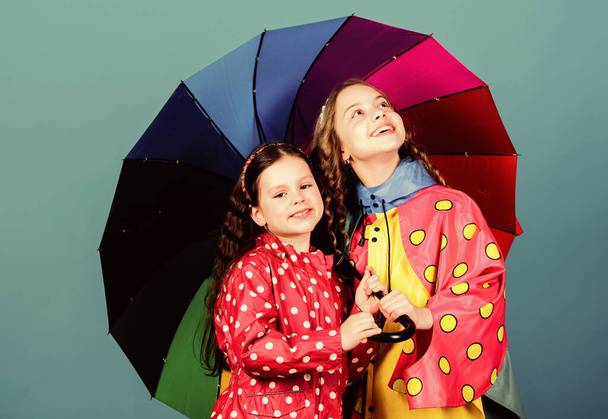 Bright umbrella. It is easier to be happy together. Be rainbow in someones cloud. Rainy day fun. Happy walk under umbrella. Kids girls happy friends under umbrella. Rainy weather with proper garments - Photo, Image