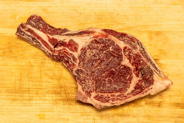 Red, juicy, raw, tomahawk steak on a wooden yellow board - Photo, Image