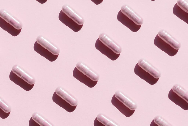 A high angle shot of pink capsules organized neatly on a pink surface - Zdjęcie, obraz