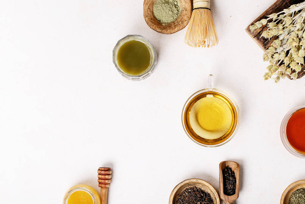 Variety of green, black and matcha tea with glass cups, wooden bowls and teapot over a white texture background. Top view. Copy Space - Foto, Bild