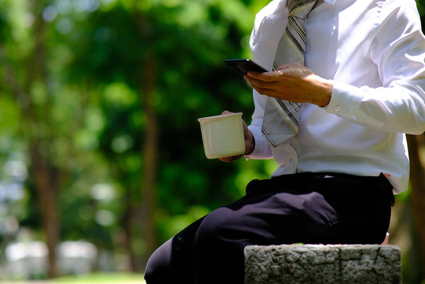 businessman using smartphone and reading a business news out door - Photo, Image