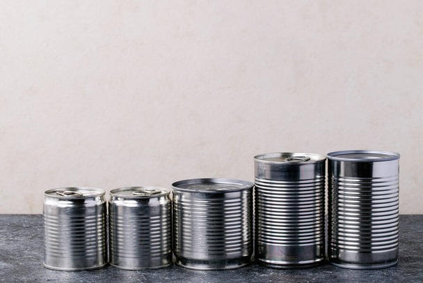 Canned food in metal cans over white texture background. Copy space. Food supply concept - Photo, Image
