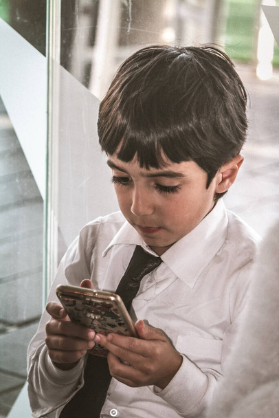 Ανδαλουσιανό νεαρό αγόρι που χρησιμοποιεί νέες τεχνολογίες πολύ σε ό, τι είναι στην οθόνη του φορητού του. Μοντέρνο στυλ, μαύρα μαλλιά μόδας και γραβάτα. Ισπανική εμφάνιση - Φωτογραφία, εικόνα
