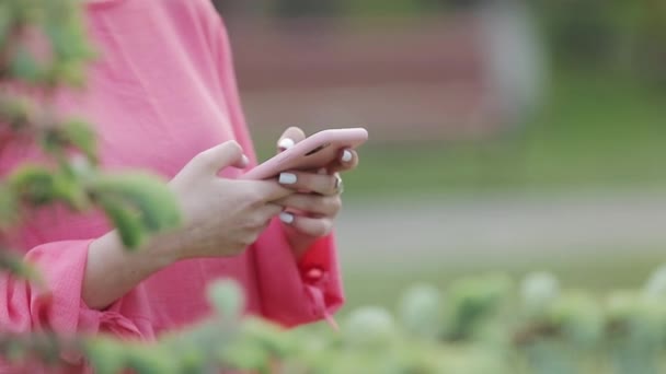 Close-up van meisje typen sms-bericht op smartphone of handen met behulp van mobiele telefoon in het park. - Video