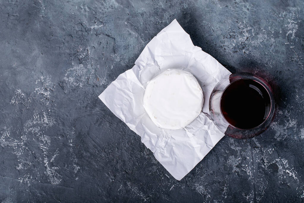 Glass of red wine served with cheese camembert over dark texture background. Top view, flat lay. Copy space - Photo, Image