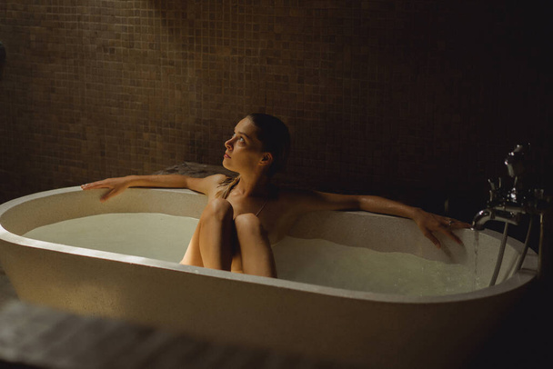 Beautiful smiling Caucasian woman posing with wet hair at bathroom, relaxing in the bath in the bathroom. young woman lying in bathtub. - Φωτογραφία, εικόνα
