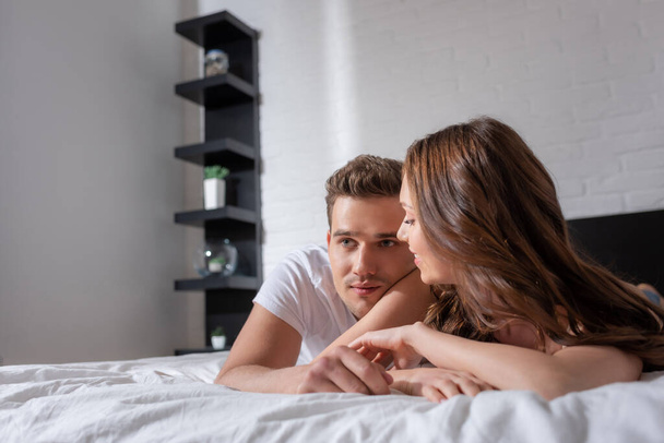 happy woman looking at handsome man lying on bed  - Photo, Image