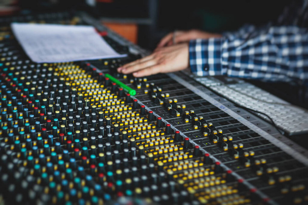 Sound editor engineer working at studio with mixing panel, mixing music and sound, stage sound mixer, boutique recording studio, working during concert performance recording, broadcasting studio - Photo, Image