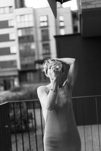 Beautiful woman on the terrace with a glass of wine is resting, laughing. black and white photo. - Fotó, kép