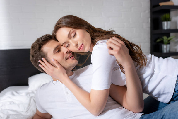 happy young woman with closed eyes hugging happy man in bedroom  - Foto, Imagen
