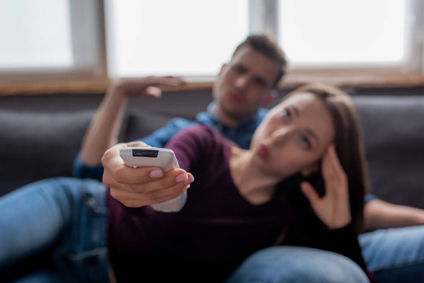 selective focus of man near woman holding remote controller from air conditioner while feeling hot  - Foto, immagini