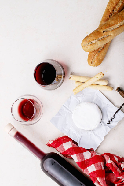 Glass of red wine served with cheese camembert and french baguette over white texture background. Top view, flat lay. Copy space - Foto, imagen