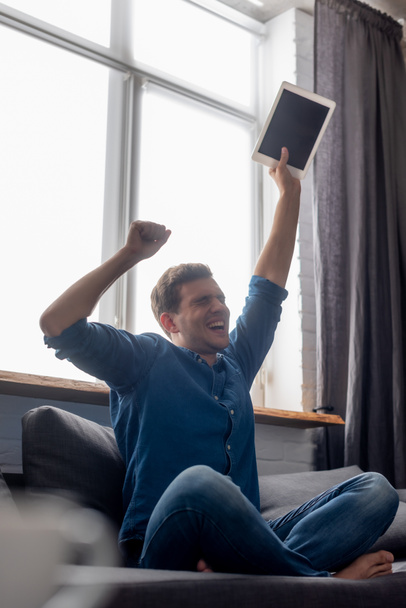 selective focus of excited man with closed eyes holding digital tablet with blank screen - Valokuva, kuva