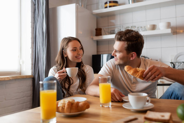 selective focus of cheerful couple looking at each other near delicious breakfast on table  - Photo, Image