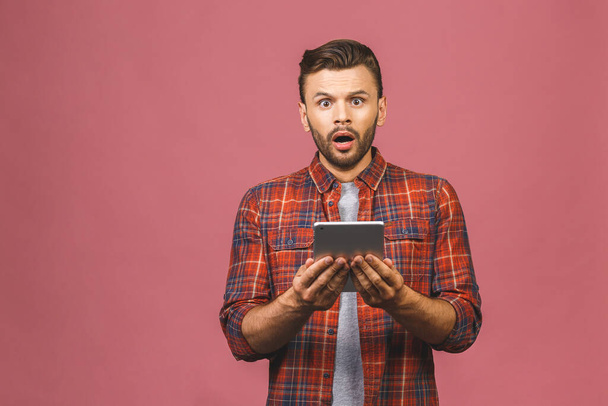Csodálkozik boldog fickó használ digitális táblagép látszó megdöbbent a szociális média hírek, meglepett férfi vásárló fogyasztó izgatott az online győzelem elszigetelt rózsaszín stúdió háttér. - Fotó, kép