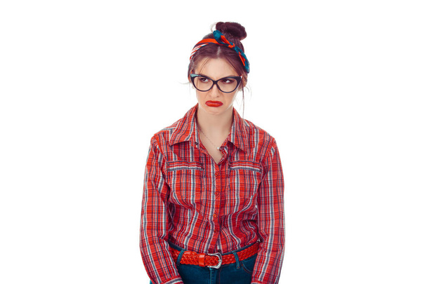 Upset woman looking to the side. Closeup portrait of a beautiful girl in red checkered shirt and jeans with retro bow on head isolated on pure white background. Mixed race, hispanic, caucasian model - Foto, imagen