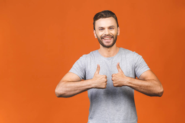 Happy young smiling handsome man showing thumbs up isolated against orange. - Φωτογραφία, εικόνα