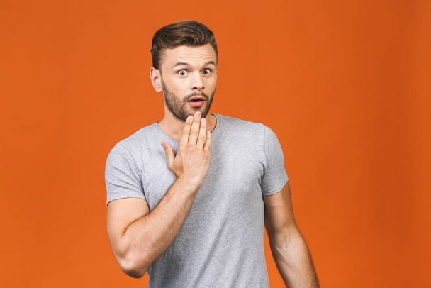 Portrait of young man with shocked surprised facial expression isolated against orange background.  - Photo, Image
