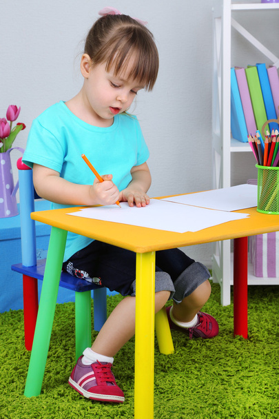 Little girl draws sitting at table in room - Fotoğraf, Görsel