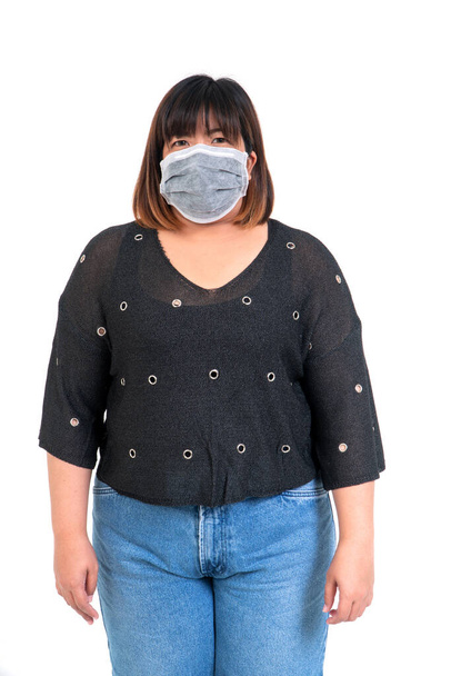 フェイスマスクをしたアジア系女性のポートレートと、白い背景のスタジオでカメラを見る。保護と隔離の概念｜コロナウイルス. - 写真・画像