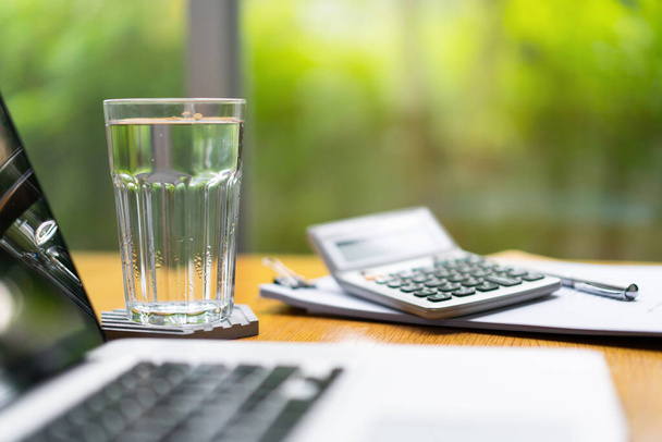 Mineral drinking water in a glass on the table. Working from home or home office concept with a relax working atmosphere. Health care, wellbeing and work life balance concept. Home office background. - Photo, image
