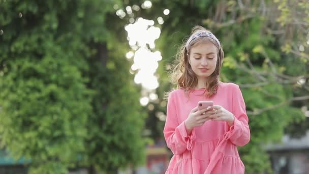 Dívka psaní textové zprávy na smartphone nebo ruce pomocí mobilního telefonu v parku. - Záběry, video