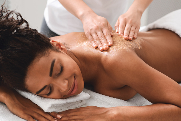 Therapist making body scrub massage for black lady - Foto, immagini