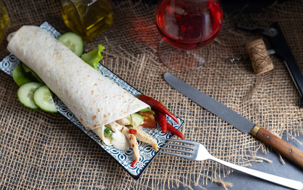 Kurczak doner kebab ze świeżymi warzywami na drewnianym stole ze szklanką wina. Widok z góry - Zdjęcie, obraz