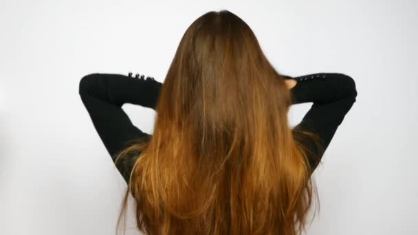 A young beautiful woman straightens her luxurious hair - Felvétel, videó