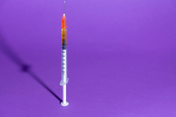 Spritze für Impfstoff oder Insulin mit seinem Schatten auf violettem Hintergrund. Gesundheitskonzepte, Impfungen, Coronarivus oder Medikamente - Foto, Bild