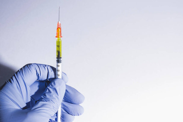 Ruka v rukavici držící injekční stříkačku na vakcínu nebo inzulín. Bílé pozadí. Zdravotní koncepce, koronární onemocnění nebo drogy - Fotografie, Obrázek