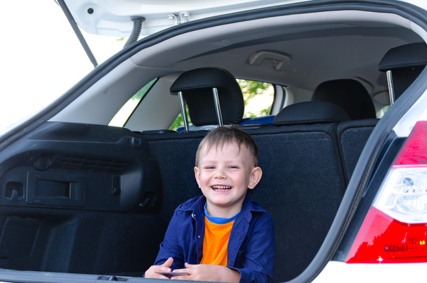 Ein lachender kleiner Junge sitzt auf der Rückbank eines Autos - Foto, Bild