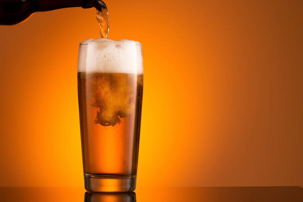 Lasi olutta vaahdolla oranssilla pohjalla - Valokuva, kuva