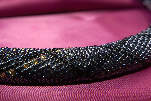 Gros plan de corde de perles, perles de graines, collier de perles. Collier de perles noires sur un satin rouge
 - Photo, image