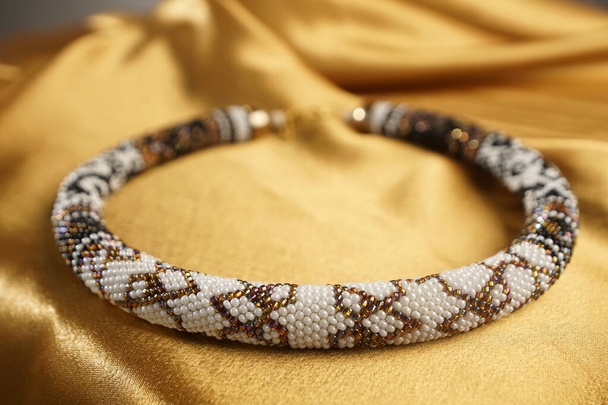 Detailní záběr perličkového provazu, perliček, náhrdelníku. Bílý náhrdelník na zlatém saténu - Fotografie, Obrázek