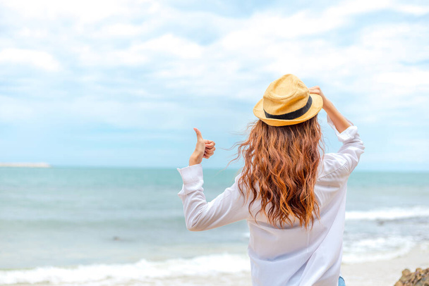 smiling young woman in sun hat and finger thumb up on beach. summer, holidays, vacation, travel concept - Φωτογραφία, εικόνα