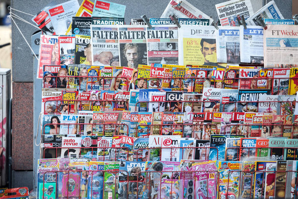 ウィーン,オーストリア- 2019年11月6日:ウィーンのダウンタウンにあるオーストリアの新聞販売店から、ドイツ語で雑誌や新聞が書かれた雑誌棚 - 写真・画像