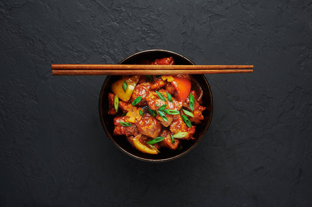 Pollo manciù in ciotola su fondo nero in cemento. Il pollo manciù è un piatto della cucina cinese indiana con petti di pollo, peperone, pomodori, salsa di soia. Copia spazio
 - Foto, immagini
