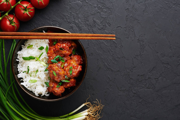 Kuřecí mandžuské v misce s rýží Basmati na černém betonovém pozadí. Kuřecí mandžuština je indická čínská kuchyně s kuřecími prsy, paprikou, rajčaty, sójovou omáčkou. Kopírovat prostor - Fotografie, Obrázek
