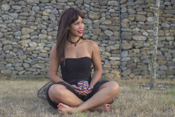 Подарункова концепція. Красива молода жінка сидить босоніж на траві з маленькою коробкою в руках
 - Фото, зображення