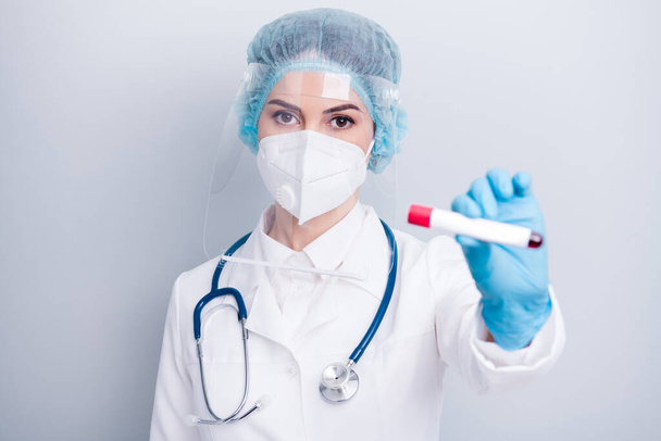 Closeup photo of virology doc viral clinic hold blood probe tube sick patient positive negative result wear coat mask facial plastic protection shield surgical cap isolated grey background - Fotó, kép