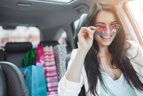 Attractive young woman in the car with shopping bags. - Foto, Imagem