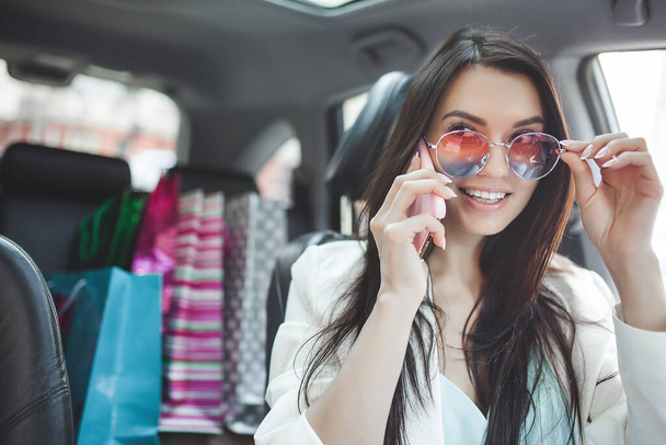 Attraktive junge Frau im Auto mit Einkaufstüten. - Foto, Bild